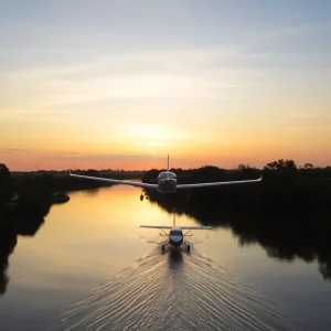 Small plane floating on tranquil river at sunset.